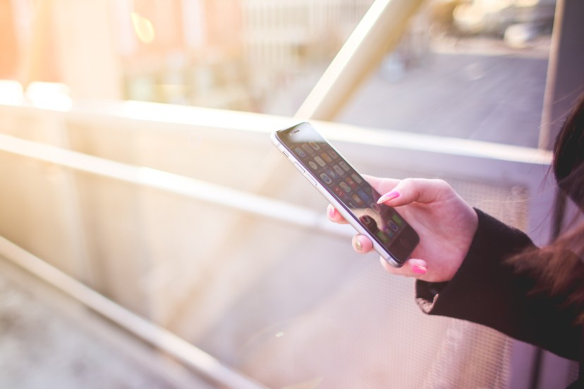 young woman holding iphone in her right hand free stock